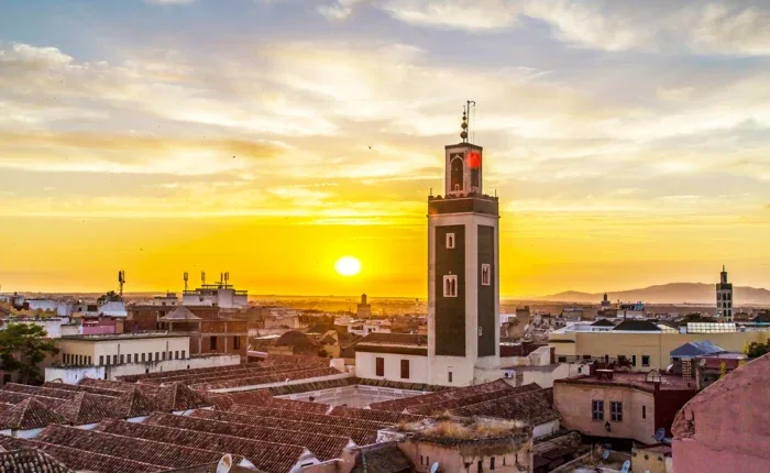 Mosque minaret rising over Moroccan rooftops at sunset