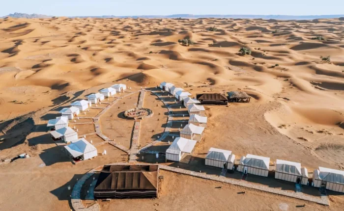 White tents arranged in a desert camp among the dunes