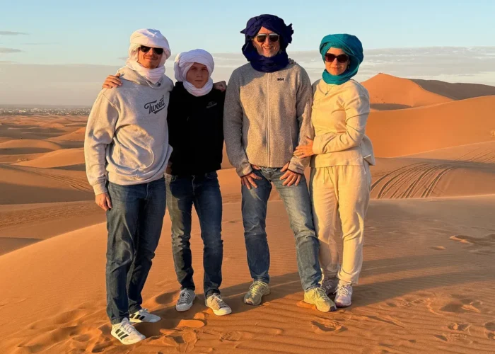 Travelers posing on Erg Chebbi sand dunes near Merzouga, Morocco